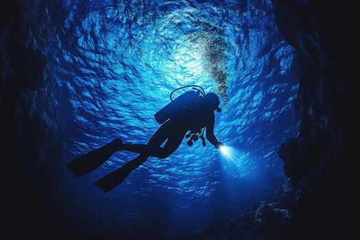 Scuba diver in the ocean with light shining from the surface photo