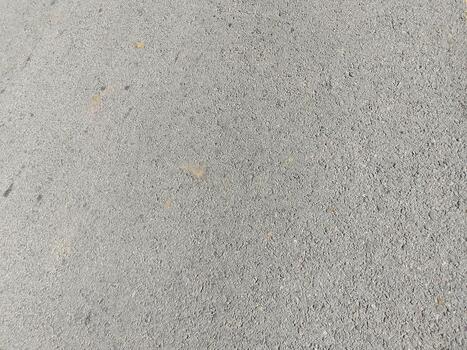 Rough Gray Concrete Surface with Embedded Pebbles and Discoloration Patterns photo