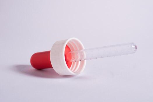 One piece of pipette with red lid isolated on horizontal plain background. photo