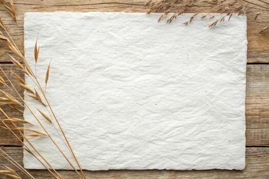 White paper on wooden background with wheat and dry grass photo
