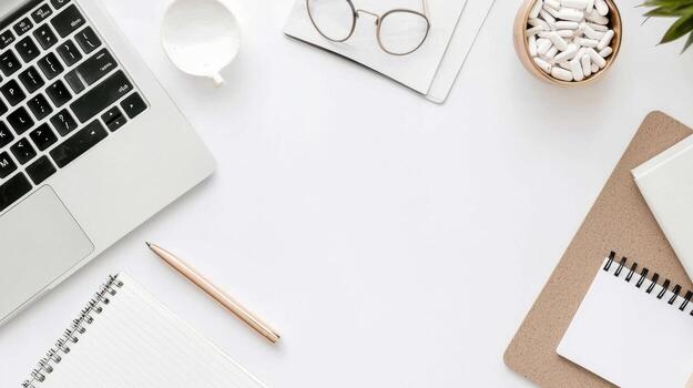 Minimalist workspace with a laptop, notebook, and stationery on a white surface. photo