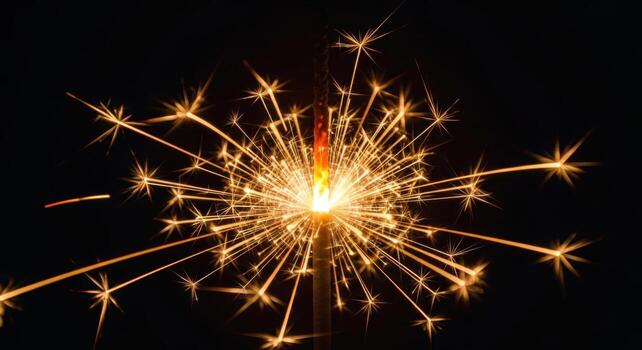 Bright golden sparkler igniting with a dazzling starburst of light on a dark background photo