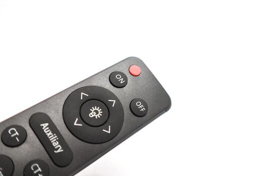 Close-up studio shot of a black remote control with various buttons on a white background photo