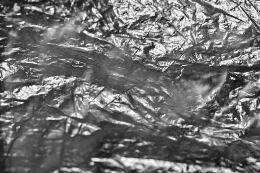 Crumpled aluminum foil texture, close-up view. The intricate details and reflective surface highlight the creases and folds, suitable for backgrounds, textures, and abstract themes. photo