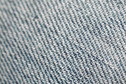 Close-Up Texture Of Blue Denim Fabric. A macro, slightly angled shot showcasing the detailed texture of blue denim fabric with its characteristic diagonal weave pattern of white and blue threads. photo