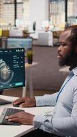 tekniker arbetssätt på vind turbin simulering i kontor, håller på med uppgraderingar. afrikansk amerikan man i rd avdelning använder sig av cad programvara på dator, håller på med förnybar energi väderkvarn teknik, kamera en video