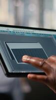 Close up of RD office employee uses touchscreen device, creating eco solar gadget prototype. Engineer using tablet to create solar powered device design with alternative energy technology video