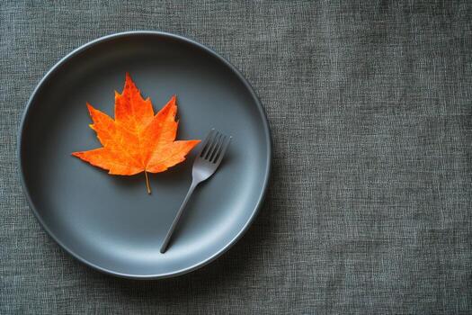A fork and a maple leaf on a gray plate photo