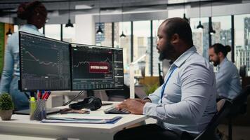 betonade stötta fast anställd på arbete larmade förbi misstänkt dataintrång varna på handel plattform instrumentbräda. orolig afrikansk amerikan man i kontor känner av dataintrång försök på handel programvara, kamera en video