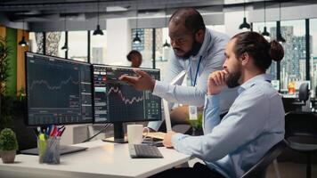 apuntalar firma personal miembros comunicar a ordenador personal escritorio a garantizar suave comercio operaciones. equipo de comerciantes en oficina haciendo lluvia de ideas, que se discute mercado tendencias y portafolio posiciones, cámara un video