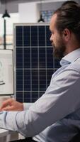 RD department researcher looking over documentation files to study solar green energy systems. Engineer using CAD software on PC to improve photovoltaics carbon footprint, camera A video