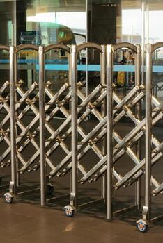 Portable retractable belt barrier stanchion on wheels for queue and crowd control at airport terminal. Empty public space with metal security fence. photo