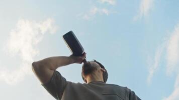 ett alkoholhaltig man vem är berusade tar en smutta av vin från en flaska, men senare han känner sjuk och kräks på kamera. låg vinkel. långsam rörelse. video