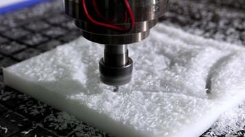 en cnc maskin är exakt träsnideri och formning en bit av vit plast i en verkstad, visa upp industriell automatisering video