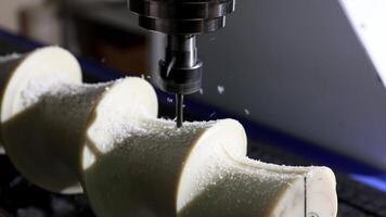 A CNC machine is precisely carving a white plastic block with a cutting tool in a modern industrial workshop video