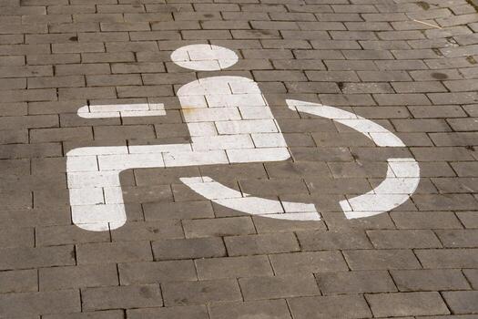 A clear wheelchair access symbol is prominently painted on the pavement in an urban setting, emphasizing the importance of accessibility for all photo