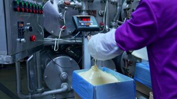 Liquid butter is pouring from the pipe into the container. Factory for the production of butter. Automated line. Food production video