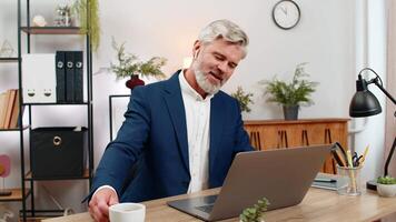 medelålders affärsman på Hem kontor koder på bärbar dator bär hörlurar lyssnande till musik medan fokusera på projekt. frilansare kille på tabell åtnjuter den rytm skriver koda leverera programvara funktion. video