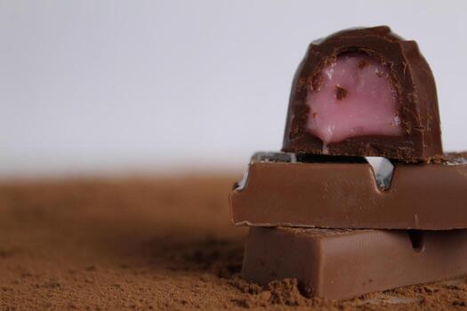 a Chocolate candy lies on chocolate and cocoa on a white background with a place for text and copyspace photo