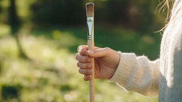 Hand holding paintbrush outdoors photo