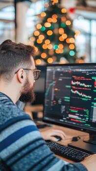 Man analyzing financial data at computer with christmas tree in background photo