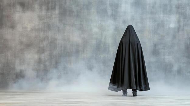 A person in a black cloak standing in front of a wall photo