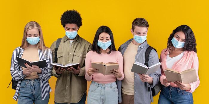 Learning and knowledge in university library during COVID-19 epidemic. Generation z busy international people in protective masks read books, isolated on orange background, studio shot, empty space photo