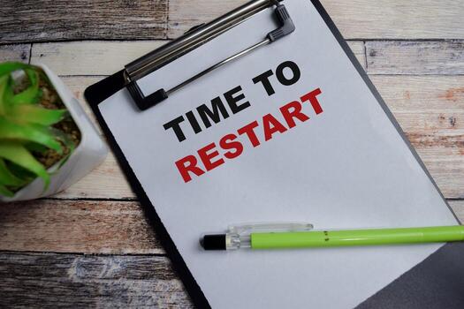 Concept of Time to restart write on clipboard isolated on Wooden Table. photo