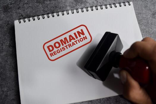 Red Handle Rubber Stamper and Domain registration text above book isolated on wooden background photo