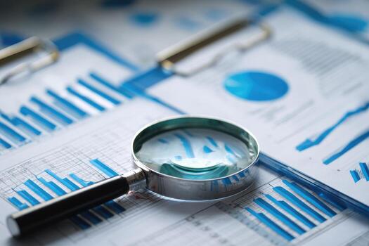 Business documents, charts, and graphs under a magnifying glass photo