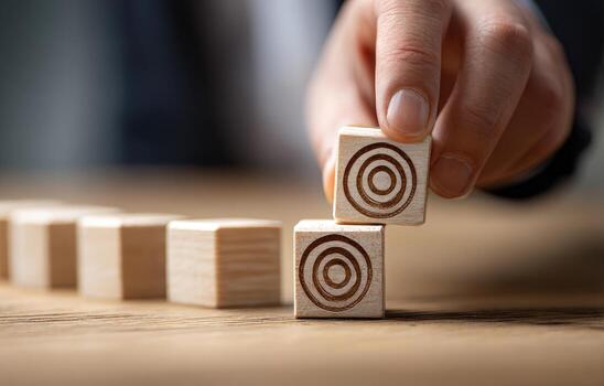 Hand placing a target-shaped wooden block onto a row of similar blocks photo