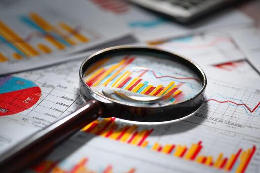 Magnifying glass focused on financial charts and graphs photo