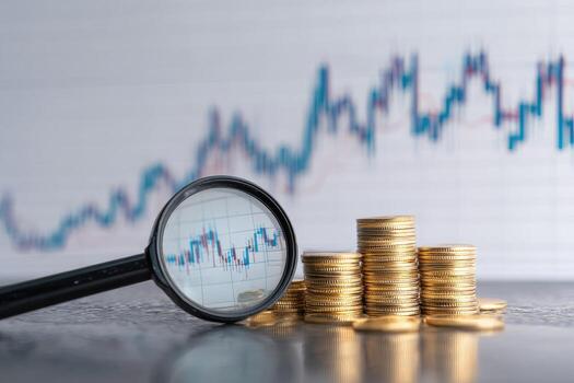 Magnifying glass over financial chart with stacks of gold coins photo