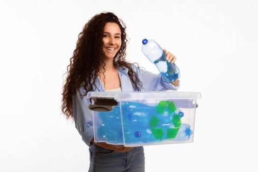 Smiling Female Putting Plastic Bottle To Box With Recycling Symbol Sorting Waste Smiling To Camera Standing Over White Background In Studio. Recycle Junk Disposal Concept photo