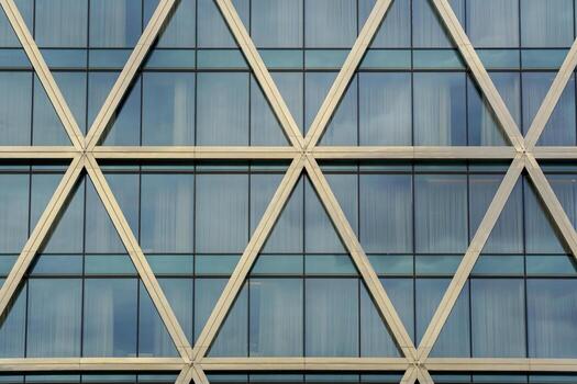 A building facade features a repeating pattern of triangular metal beams filled. photo