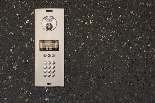 moderno intercomunicador sistema con numérico teclado, vocero, y cámara instalado en oscuro texturizado Roca pared. seguro acceso controlar dispositivo para residencial o comercial edificios, la seguridad y comunicación foto