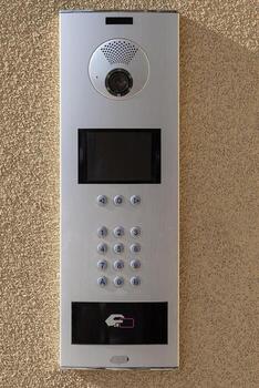 moderno intercomunicador sistema con cámara, teclado, y sin contacto tarjeta lector instalado en texturizado pared. inteligente hogar seguridad dispositivo para acceso controlar y visitante comunicación en residencial edificios foto