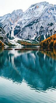 Calm alpine lake reflecting snow capped mountains and autumn trees with rowboats photo