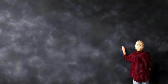 Person writing on a large dark gray wall photo
