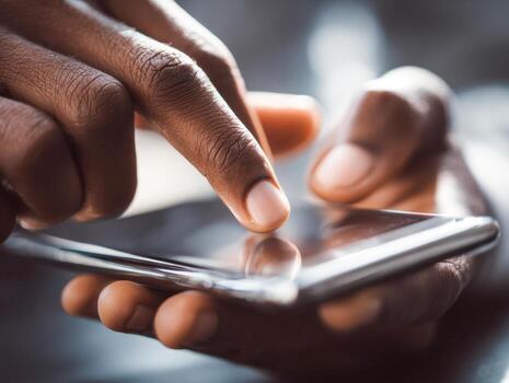 Close-up of a person using a smartphone with one hand holding the device and the other hand tapping the touchscreen in a modern technology interaction setting photo