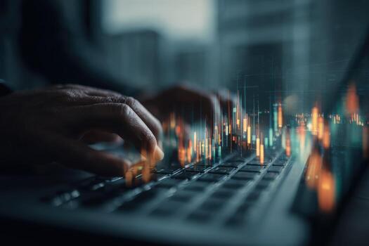 Close-up of hand typing on a laptop with digital stock market data overlay photo