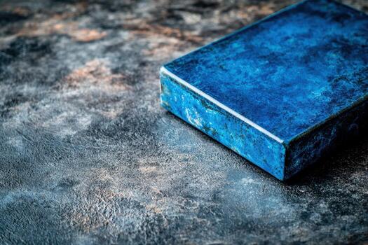 Blue stone object resting on textured dark surface under natural light photo