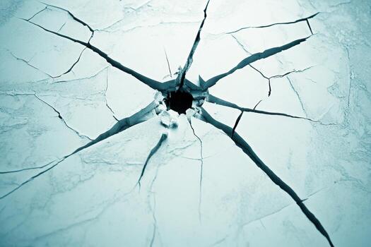 Cracked surface revealing hole with distinct fissures in an icy blue setting photo