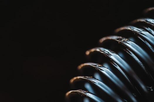 Close-up view of a spiral metal coil showing texture and detail against a dark background photo