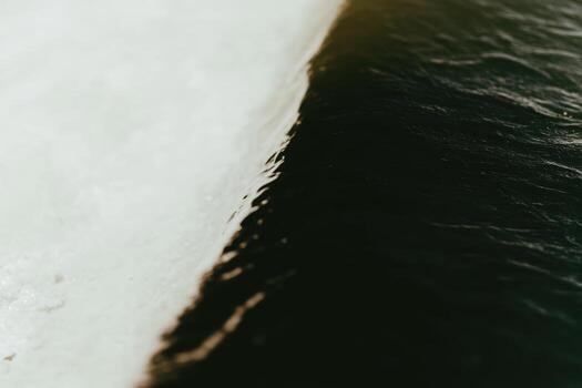 Contrast of frozen ice and flowing water at the edge of a river during winter photo