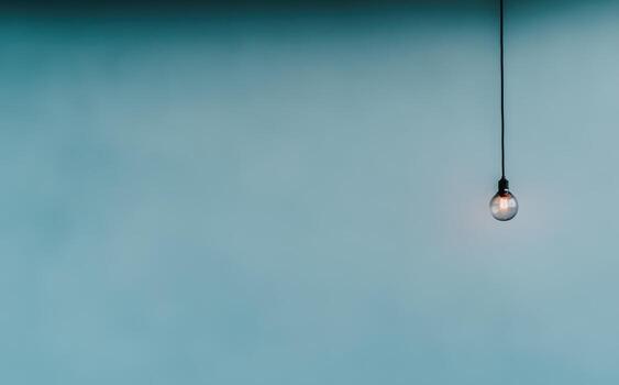 Soft lighting hangs from a cord against a serene blue background photo