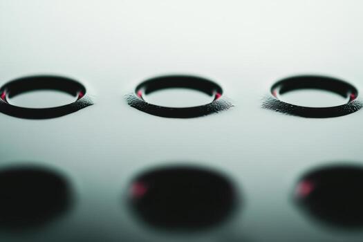 Close-up view of black circular depressions on a smooth surface in dim lighting photo