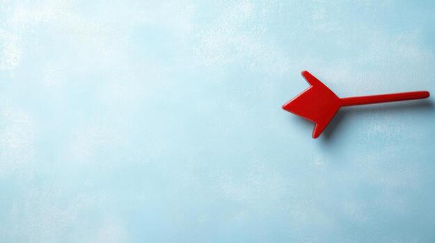 Red arrow pointing left on light blue textured background with empty copy space for text directional concept photo