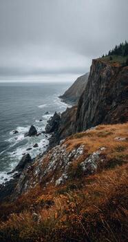 A rocky cliff overlooking the ocean on a cloudy day photo