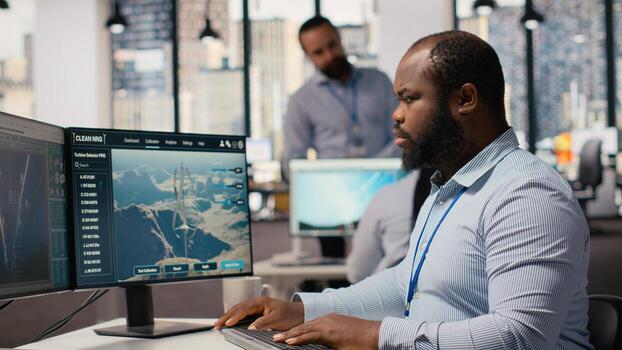 Employee using electric grid optimization tools with wind farm layout modeling software to enhance clean energy systems. Engineer doing power lines and futuristic wind turbine simulations, camera B photo